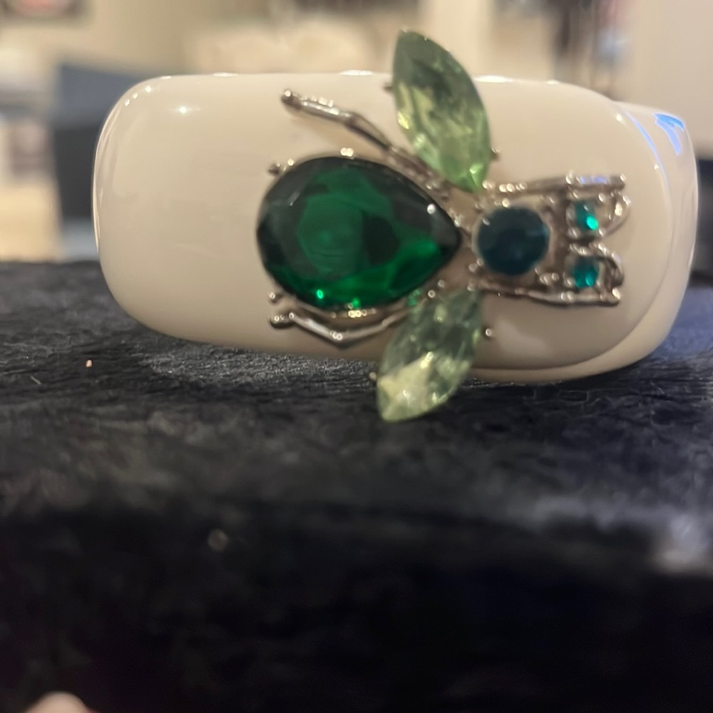 White hinge bracelet with green stone insect on top